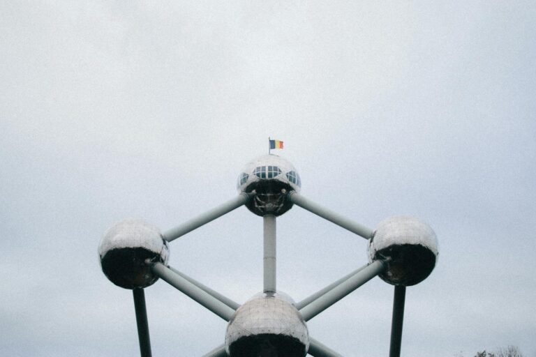 View of the Atomium structure in Brussels, showcasing its futuristic design with a Belgian flag on top.