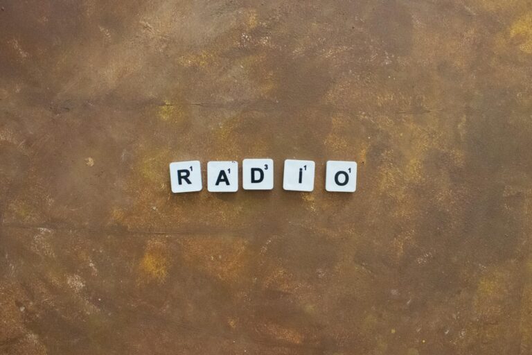 Close-up of Scrabble tiles spelling 'Radio' on a rustic brown background.