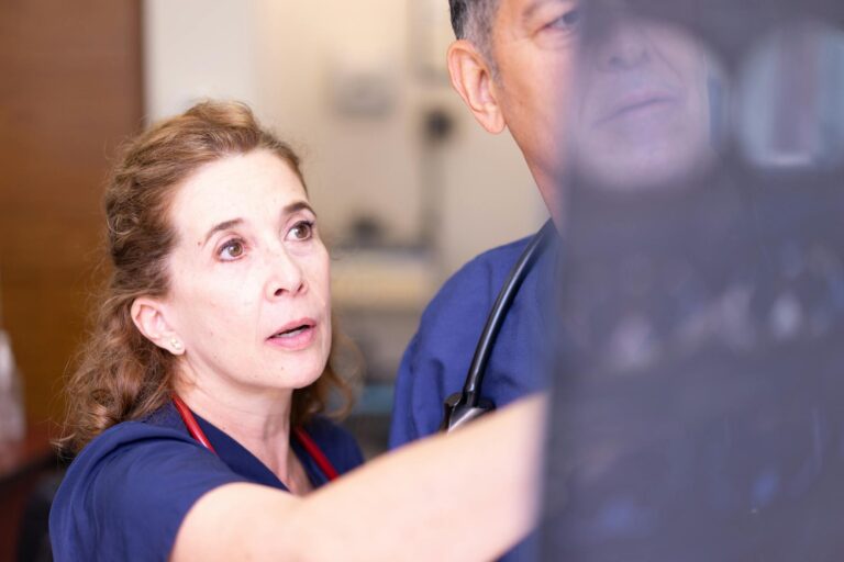 Doctors in scrubs examining an X-ray in a clinical setting for diagnosis.