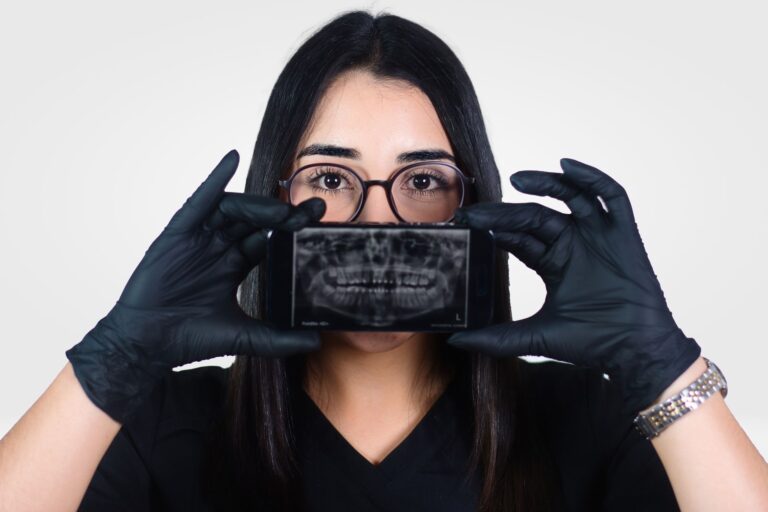 Female dentist holding a dental X-ray displayed on a smartphone, promoting oral health awareness.