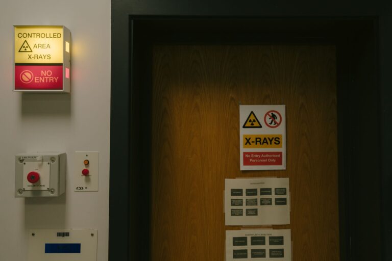 Warning signs on a wooden door indicating a controlled X-ray area with no entry restriction.