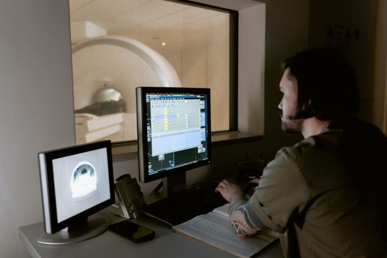 A radiologist examines MRI scan results on computer monitors in a medical facility.