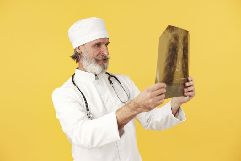 Bearded doctor examining an X-ray against a vibrant yellow backdrop. Professional healthcare image.