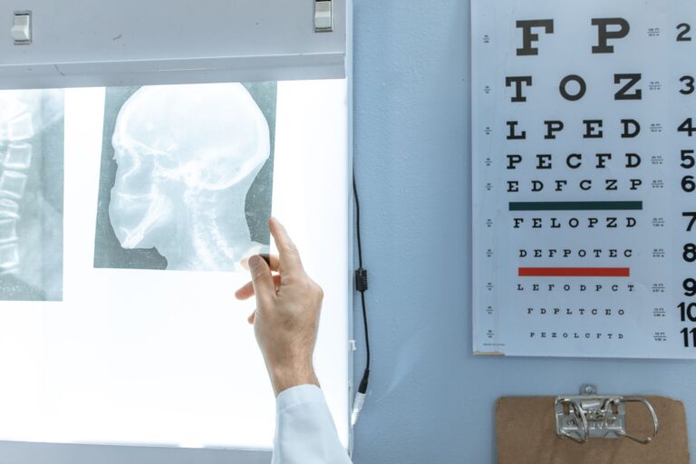 A medical professional checks an X-ray next to a Snellen eye chart in a clinic.