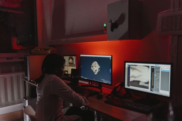 A female veterinarian studies x-ray images in a dimly lit office, focusing on animal healthcare and diagnostics.