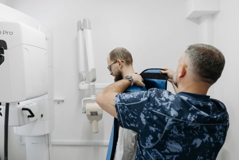 A healthcare professional helps a patient prepare for an X-ray examination in a modern clinic.