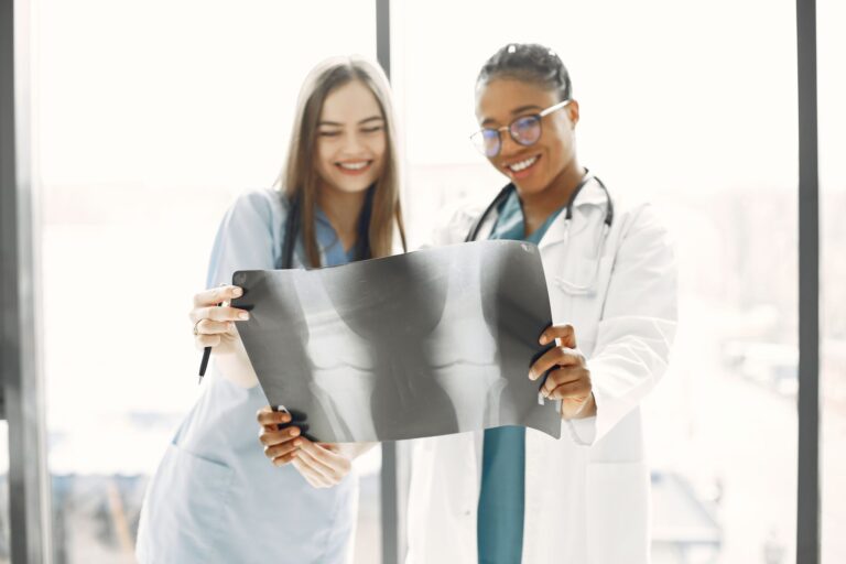 Two smiling healthcare professionals analyzing an X-ray in a brightly lit hospital room.