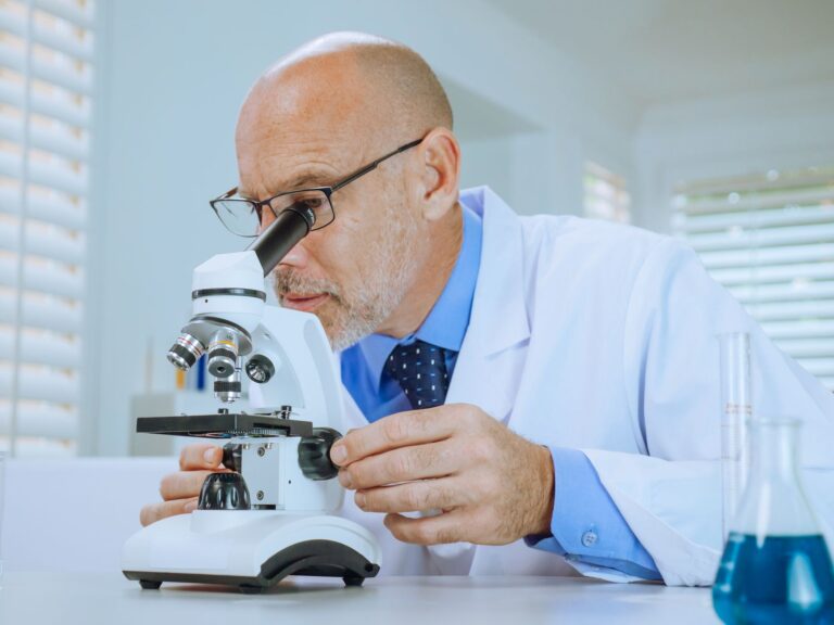Scientist examining samples through a microscope in a modern laboratory setting.