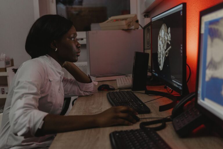 Veterinarian analyzing a 3D skull scan on dual monitors in an office setting.