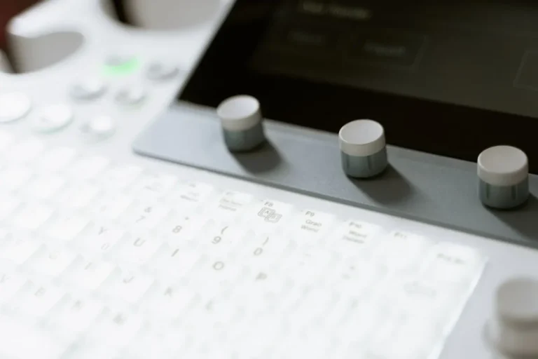 Detailed view of ultrasound machine showing keyboard and control knobs in a medical setting.